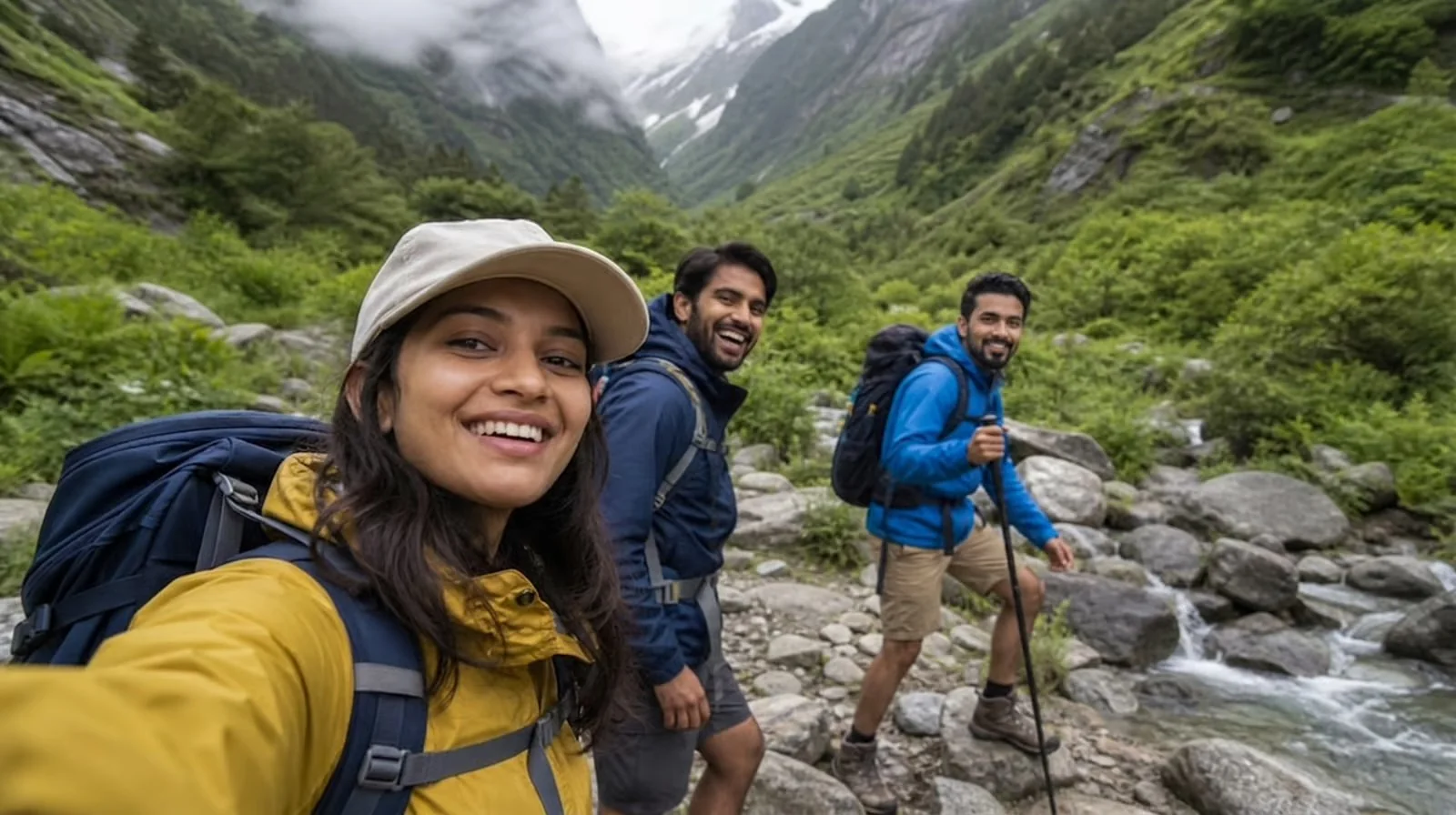Frame 4 — On Foot, hiking selfie of the trio crossing a boulder stream in a green valley